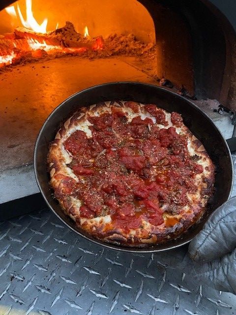 A pizza is being cooked in a pan in front of an oven