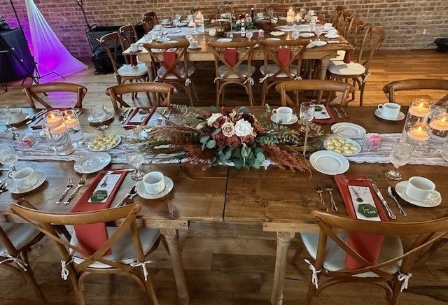 A long wooden table with plates , candles , and flowers on it.