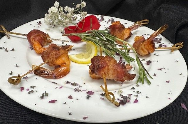 A white plate topped with shrimp wrapped in bacon