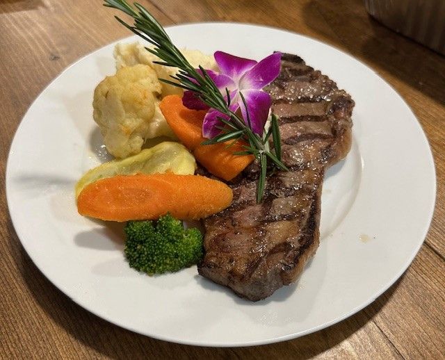 A white plate topped with a steak and vegetables