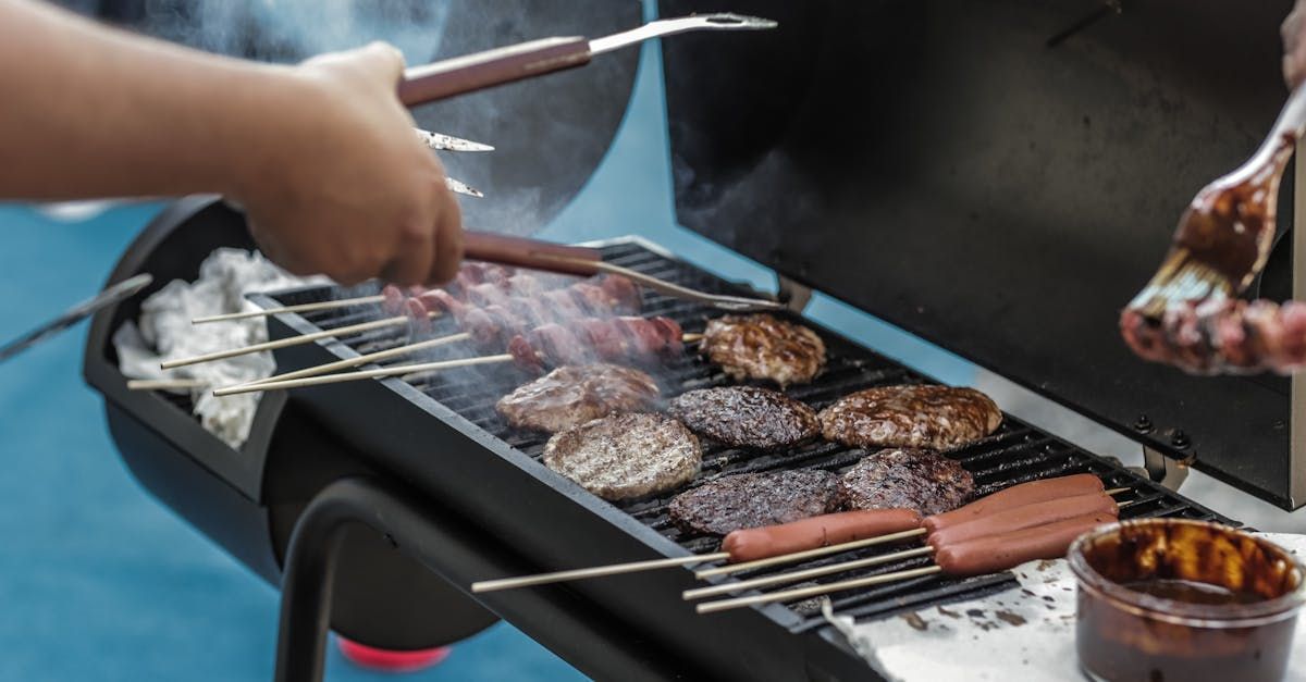A person is grilling hamburgers and hot dogs on a grill.