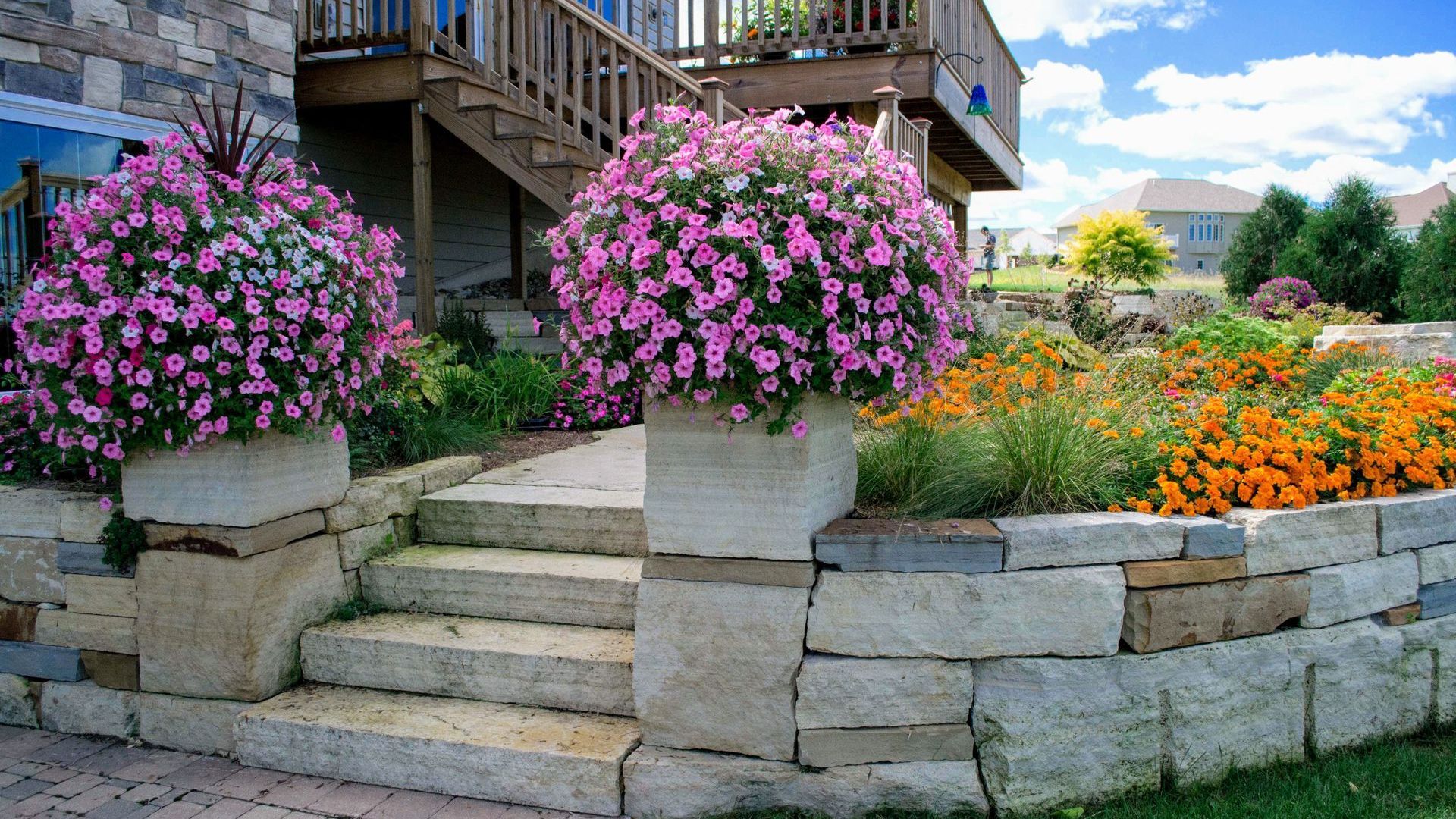 A stone wall with stairs and flowers in front of a house.