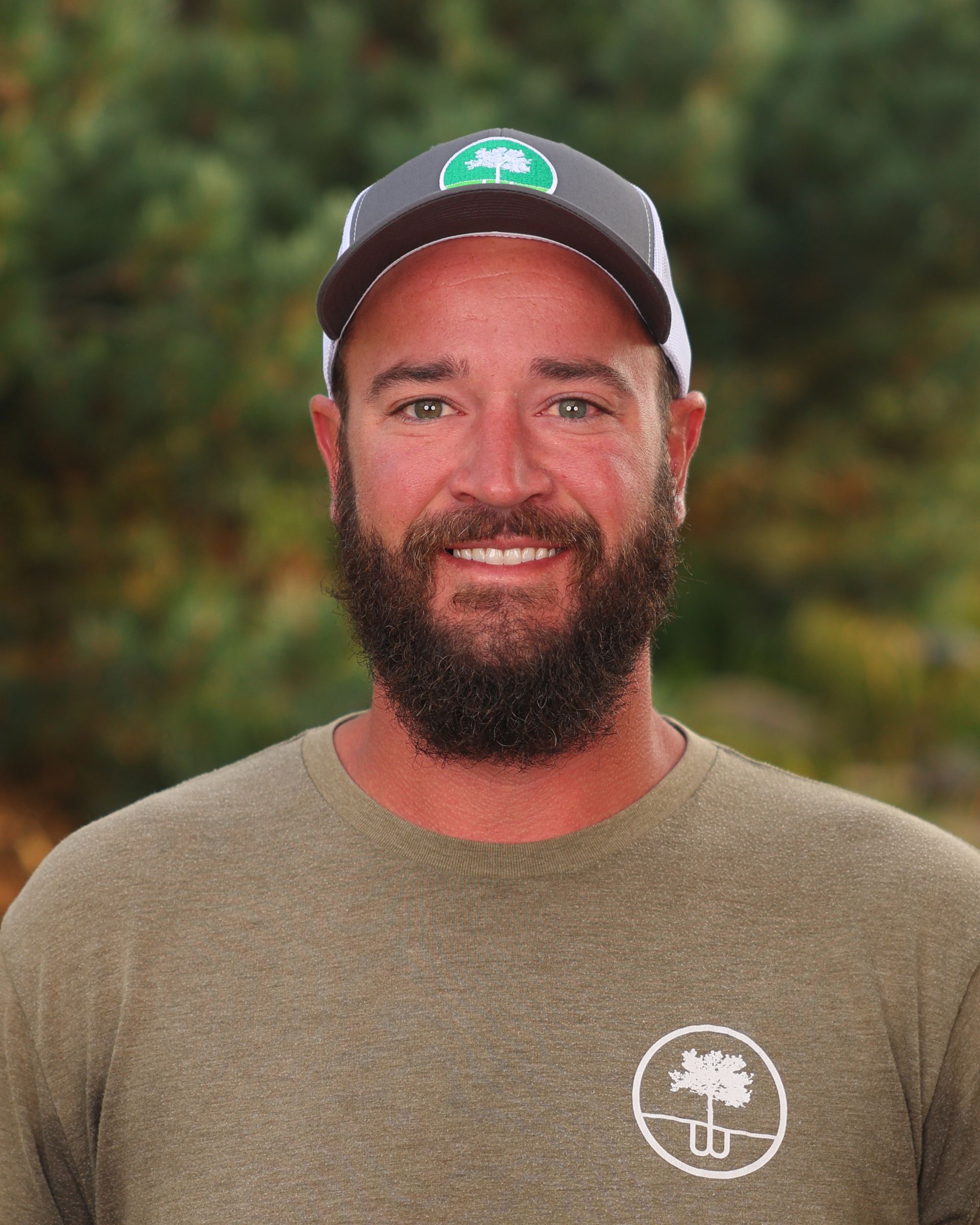 A man with a beard wearing a hat and a green shirt