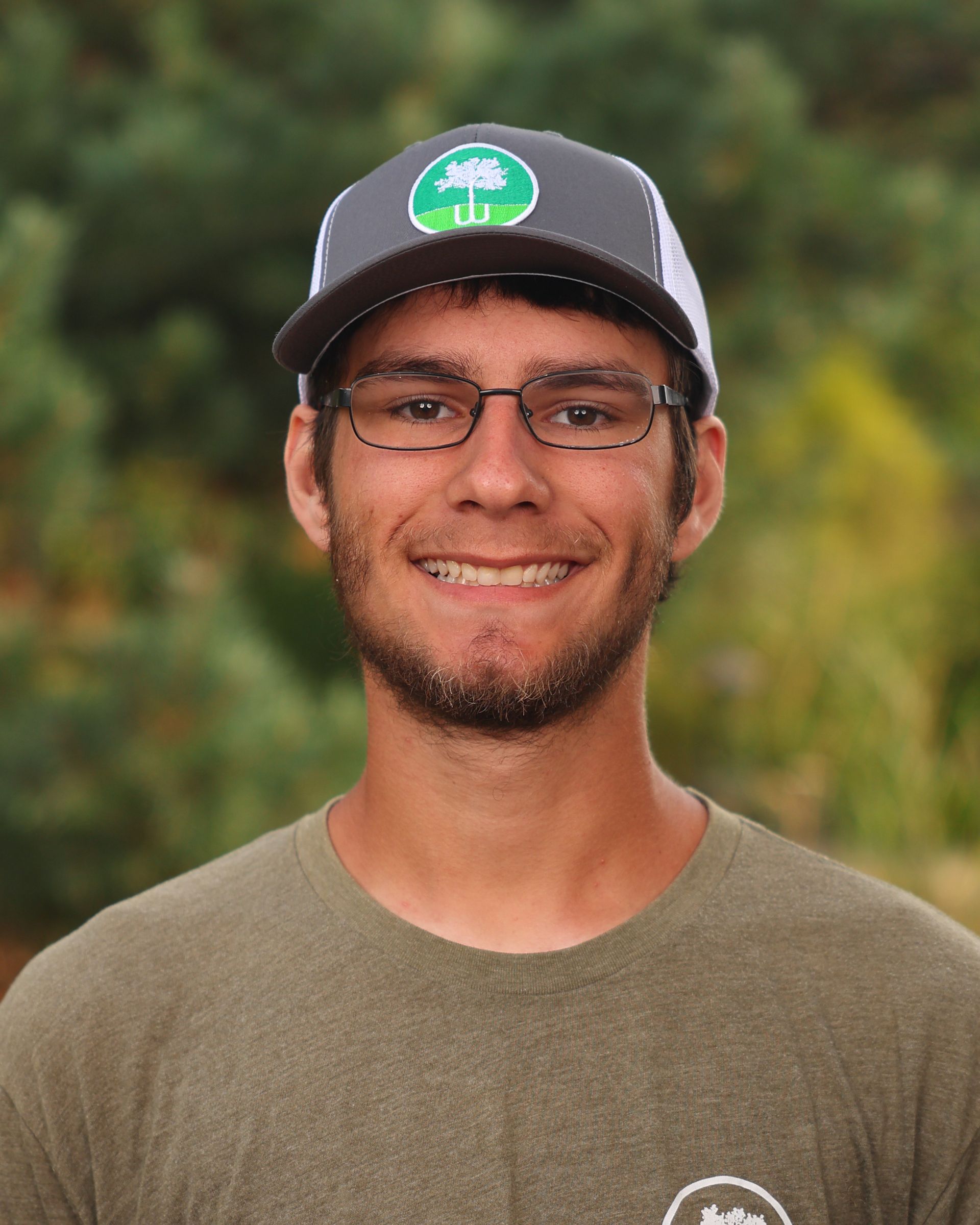 A man wearing a hat and glasses is smiling for the camera