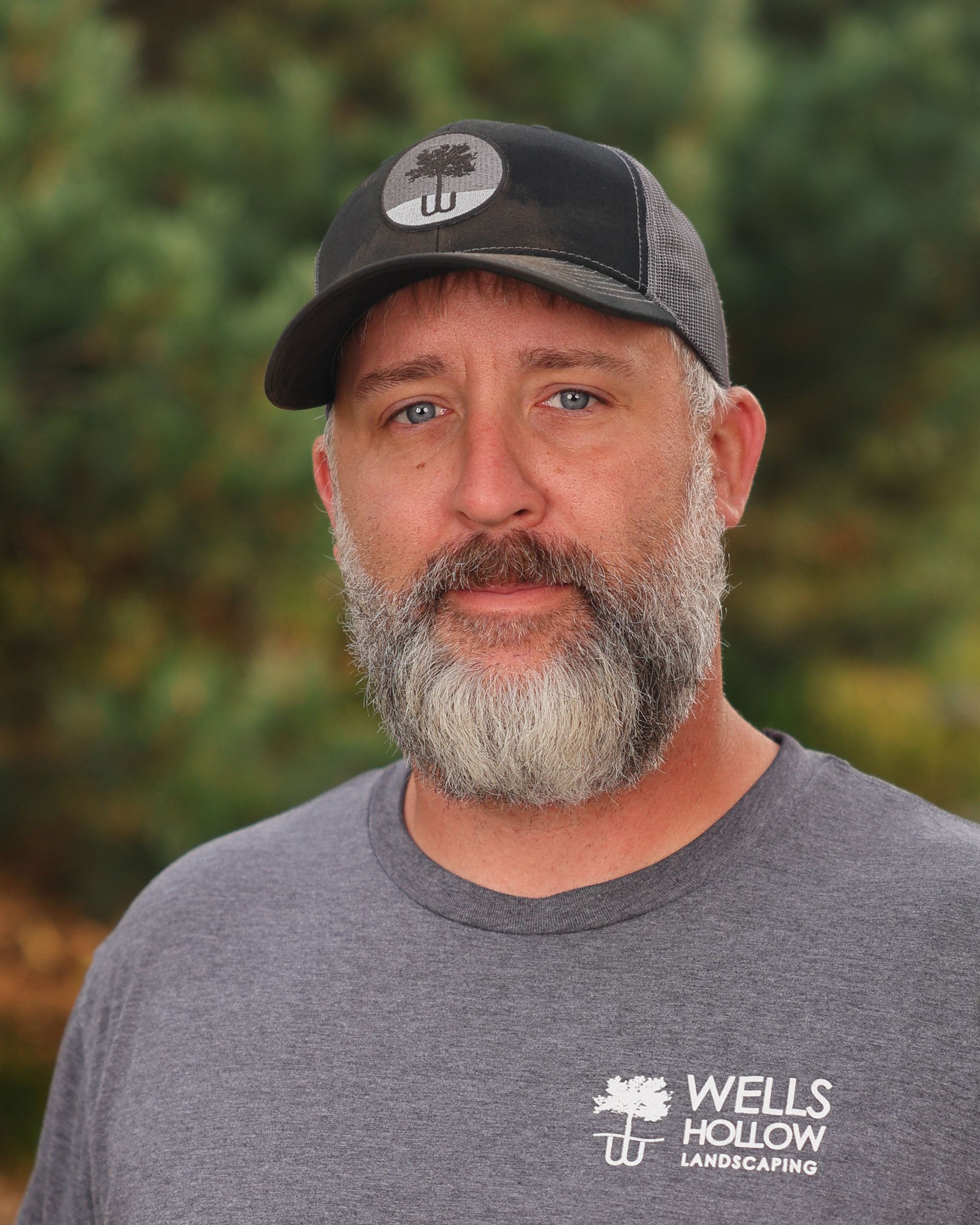 A man with a beard wearing a wells hollow landscaping shirt