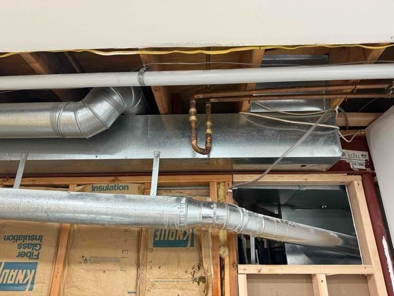 HVAC ductwork and copper pipes in a ceiling cavity. Ductwork is silver, pipes are copper.