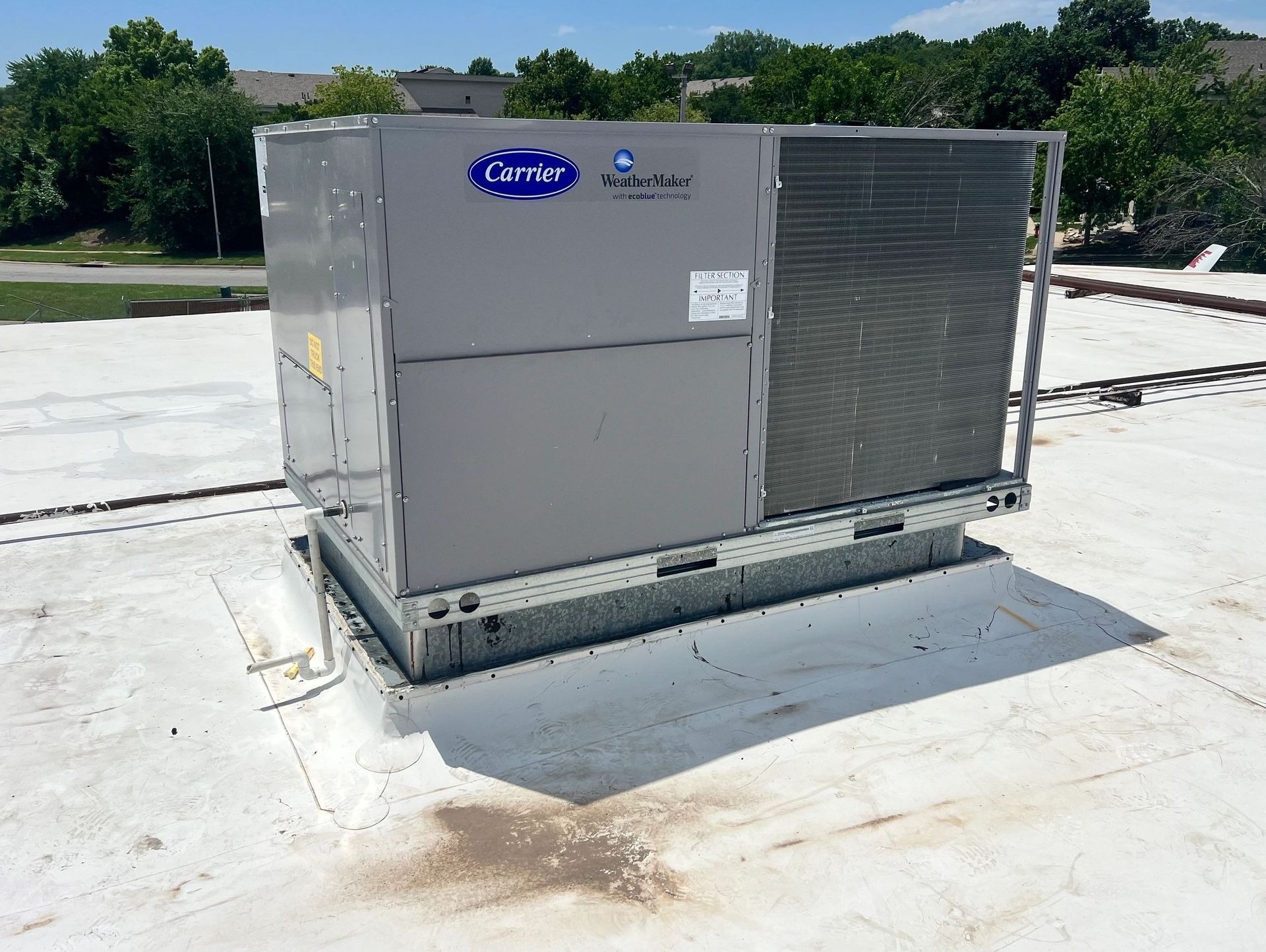 Carrier rooftop HVAC unit on a white flat roof, sunny day.