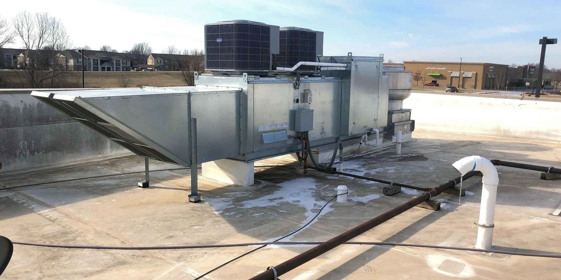 HVAC system on a rooftop. Metallic components, white pipes, a sunny day.