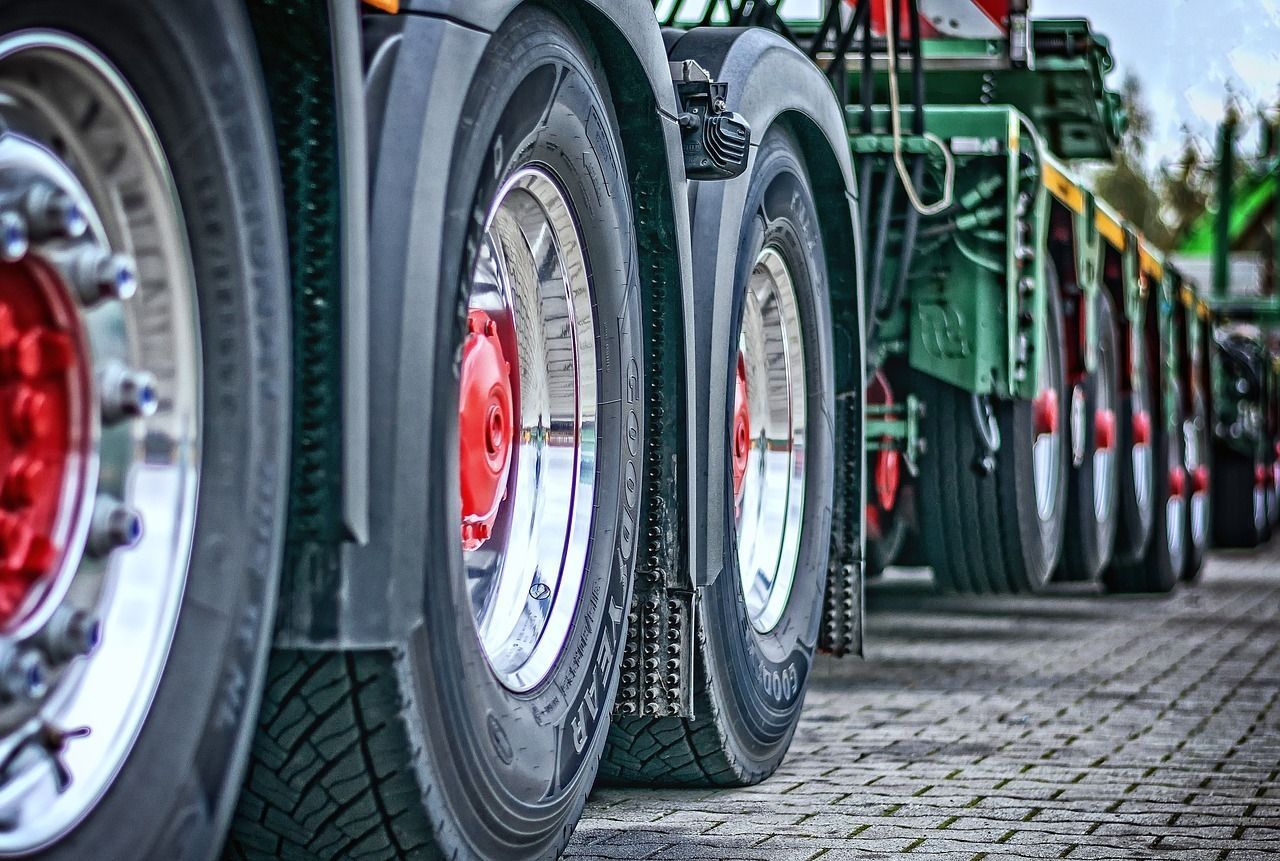 A row of semi trucks parked next to each other on a cobblestone street.