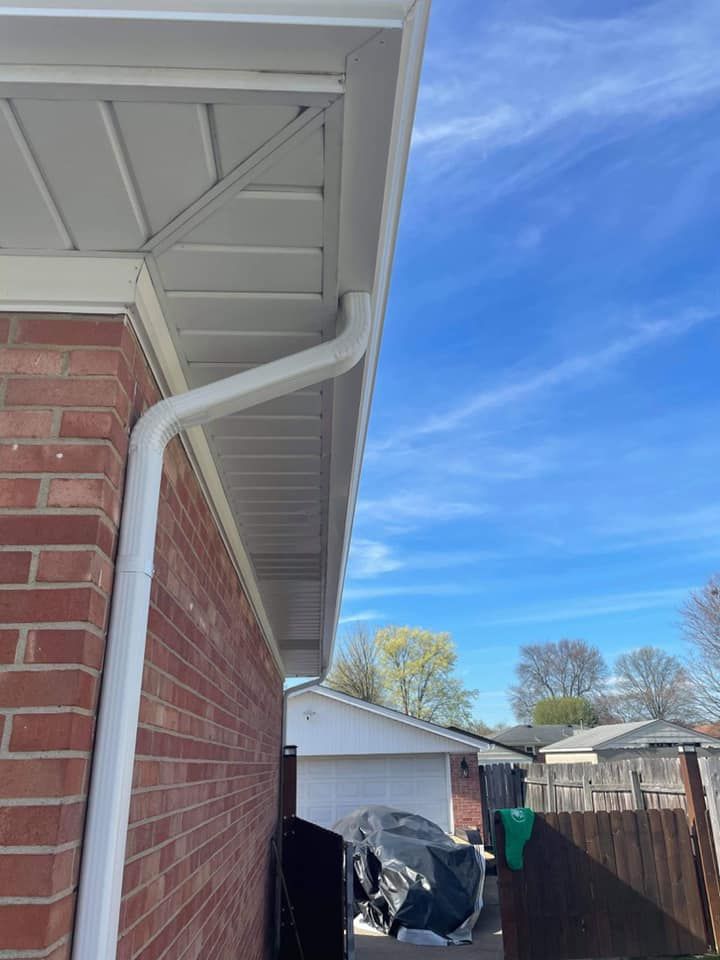 There is a white gutter on the side of a brick house.