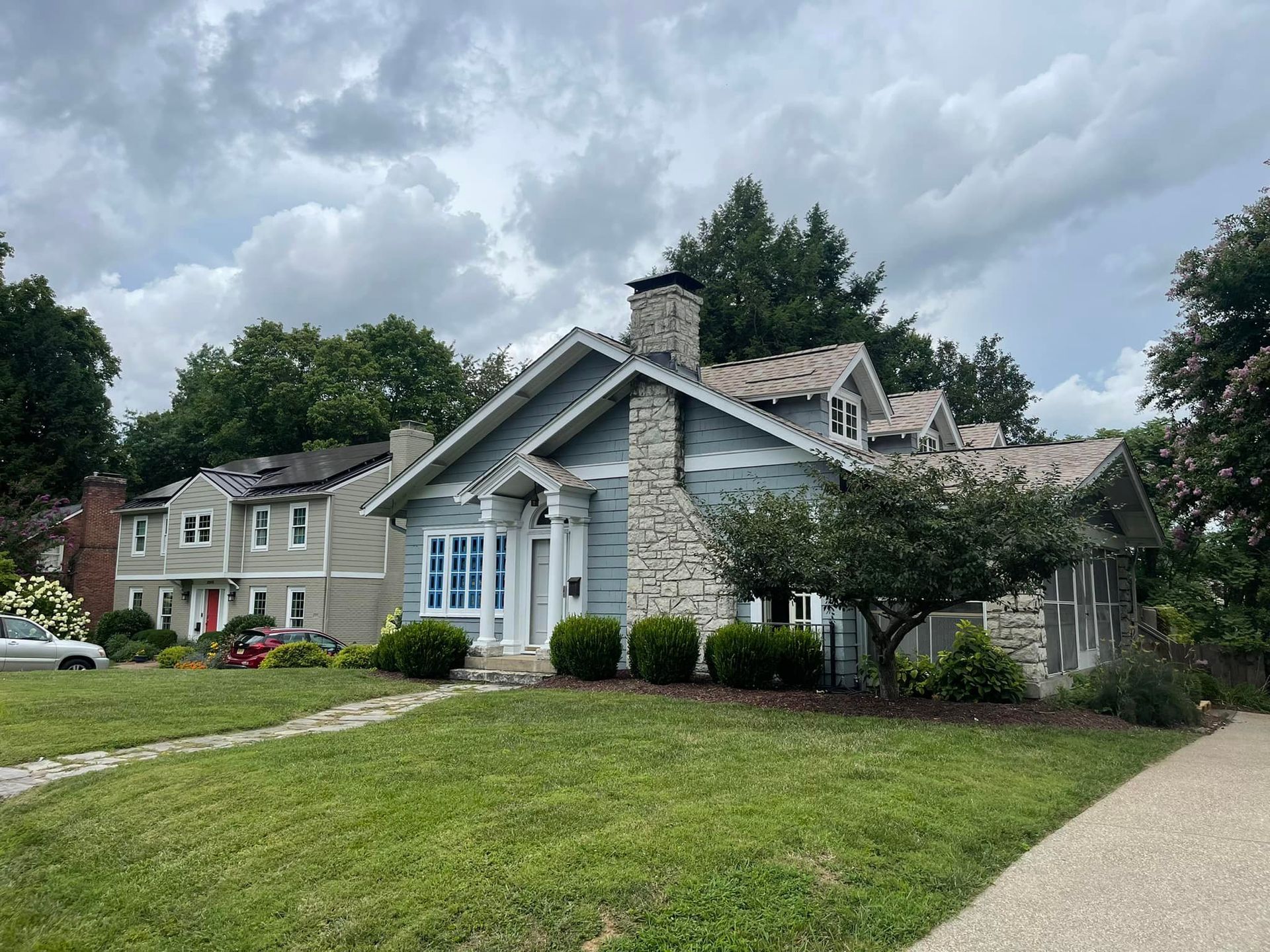 A large house with a stone chimney is sitting on top of a lush green lawn.