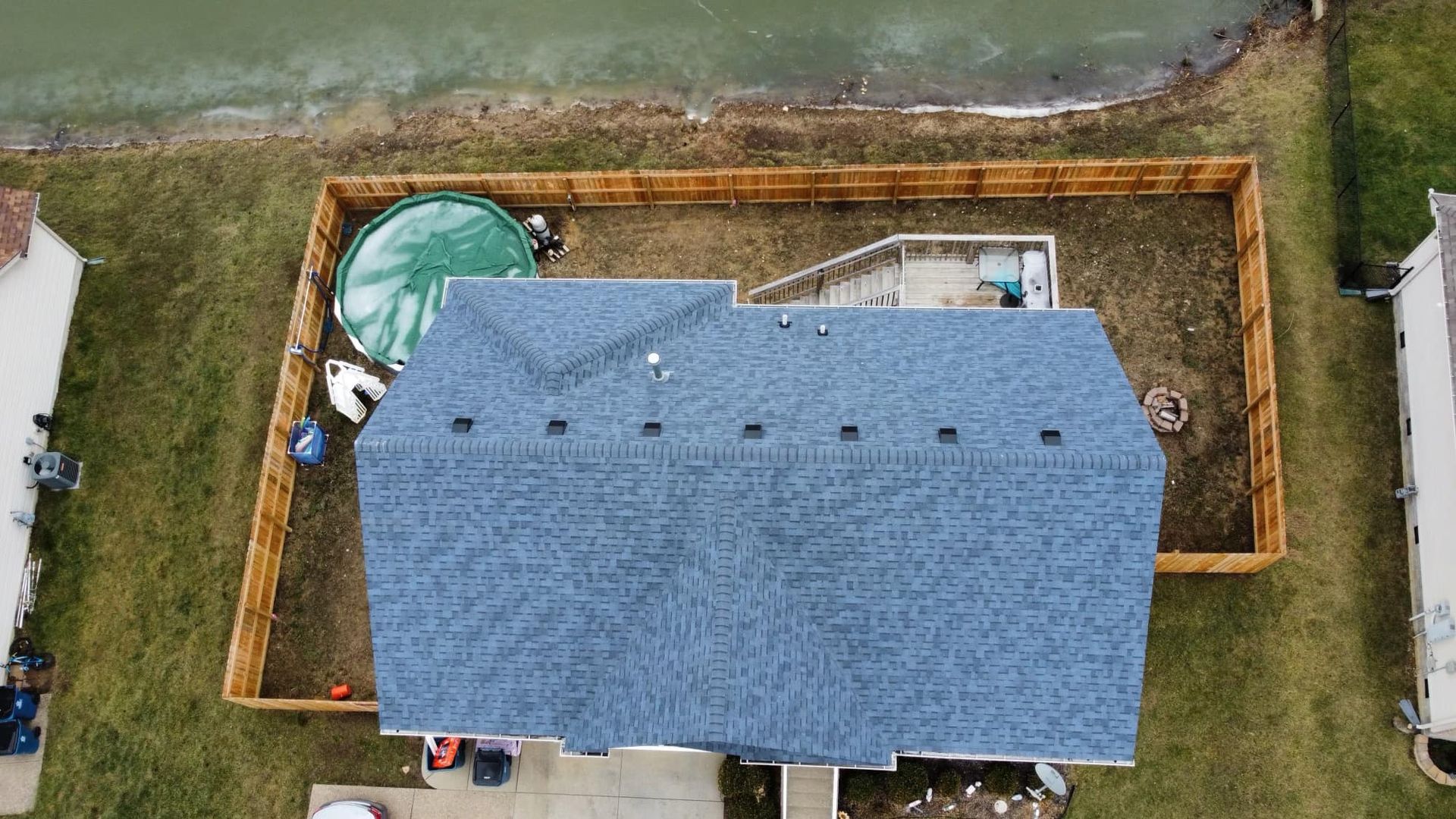An aerial view of a house with a blue roof and a wooden fence.