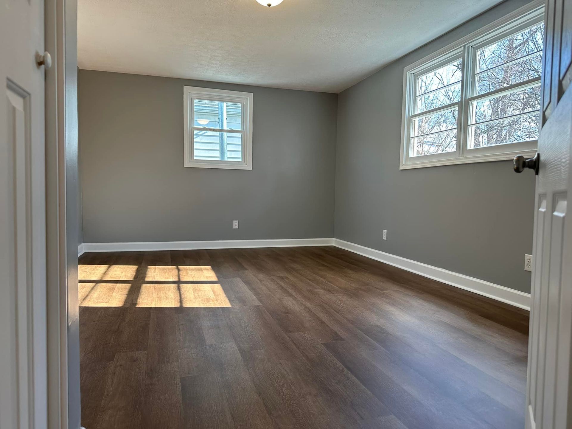 An empty room with hardwood floors and gray walls
