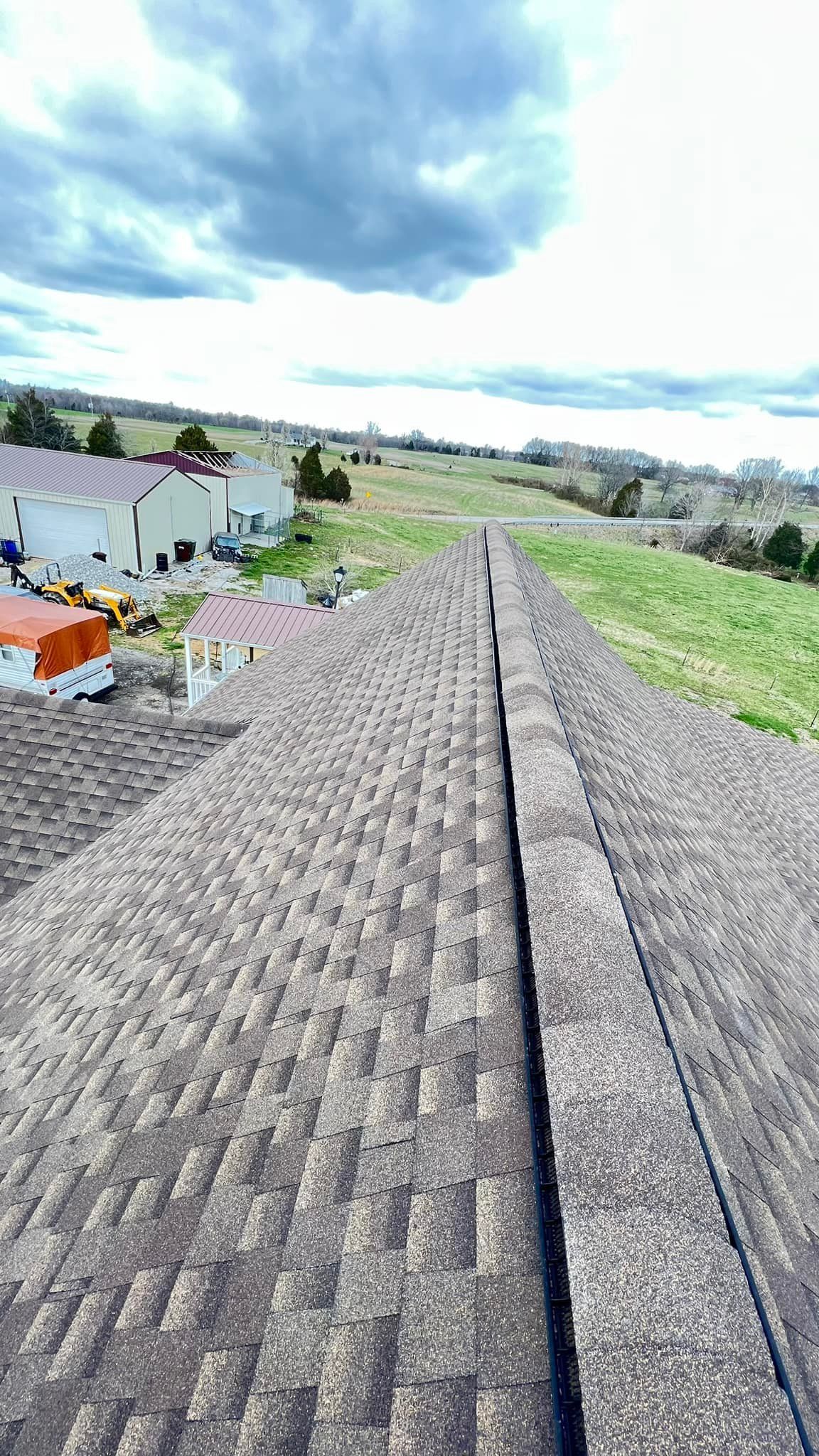 A roof with a lot of shingles on it and a house in the background.