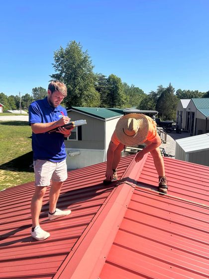 Two men are working on a red roof.