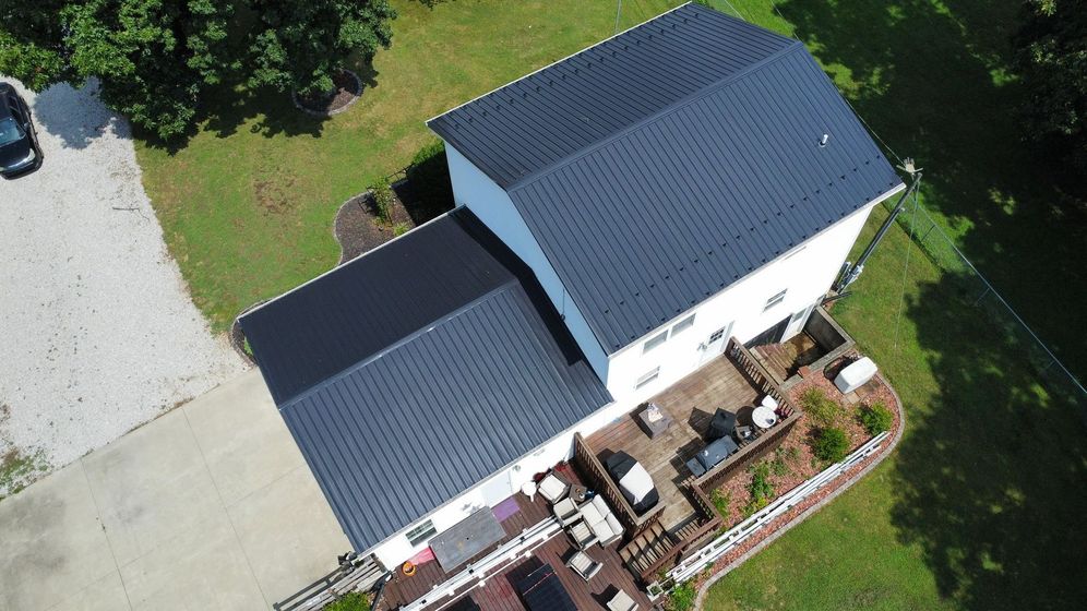 An aerial view of a white house with a black roof.