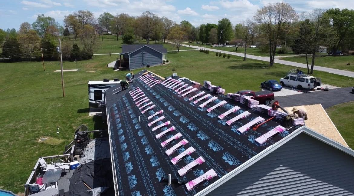 An aerial view of a white house with a black roof.
