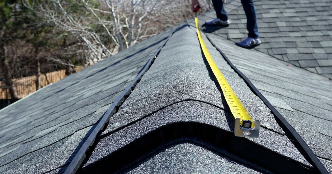 Two men are working on a red roof.