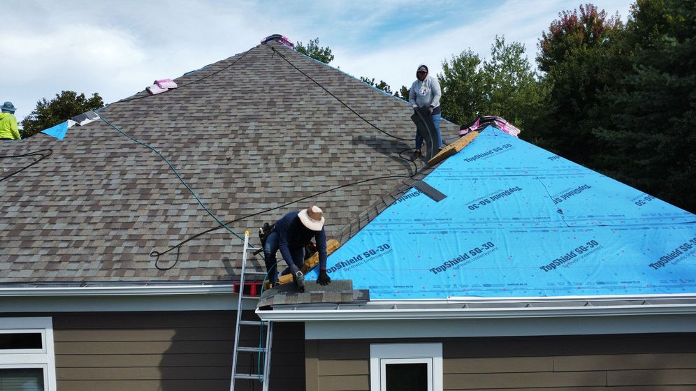 An aerial view of a white house with a black roof.
