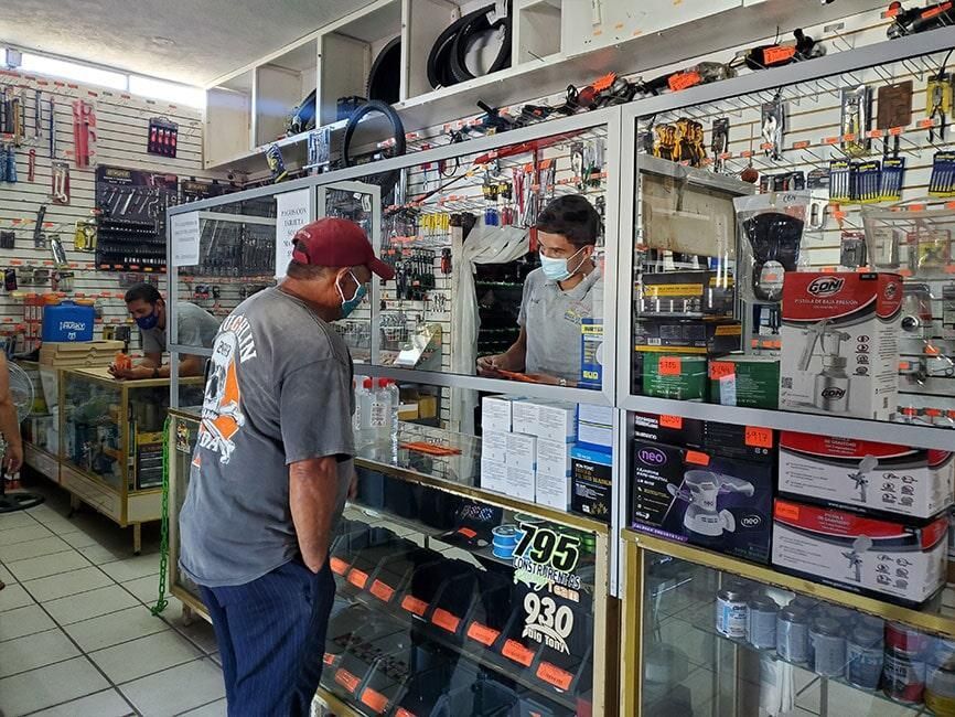 Un hombre con una máscara está parado frente a un mostrador en una tienda.