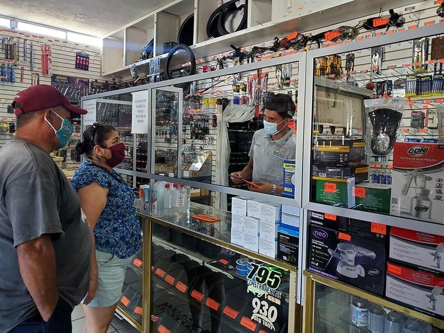 Un hombre y una mujer con máscaras están parados en una ferretería.