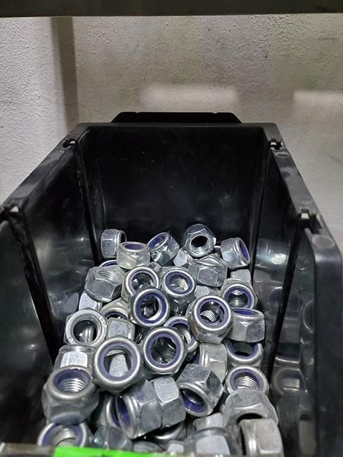 Un contenedor de plástico negro lleno de tuercas y tornillos.