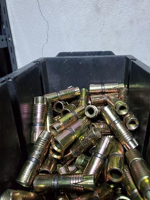 Un contenedor negro lleno de muchas piezas de metal.