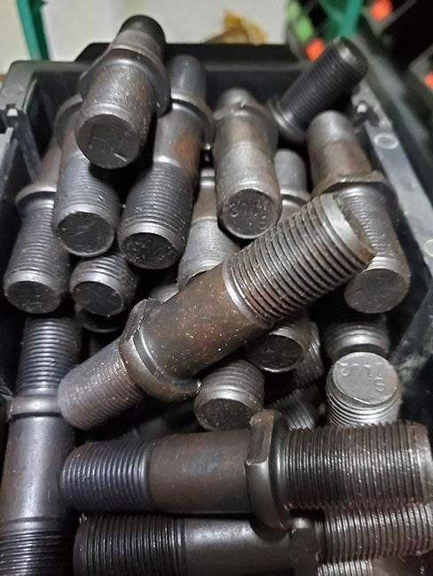 Un montón de tuercas y tornillos están apilados uno encima del otro en una caja.