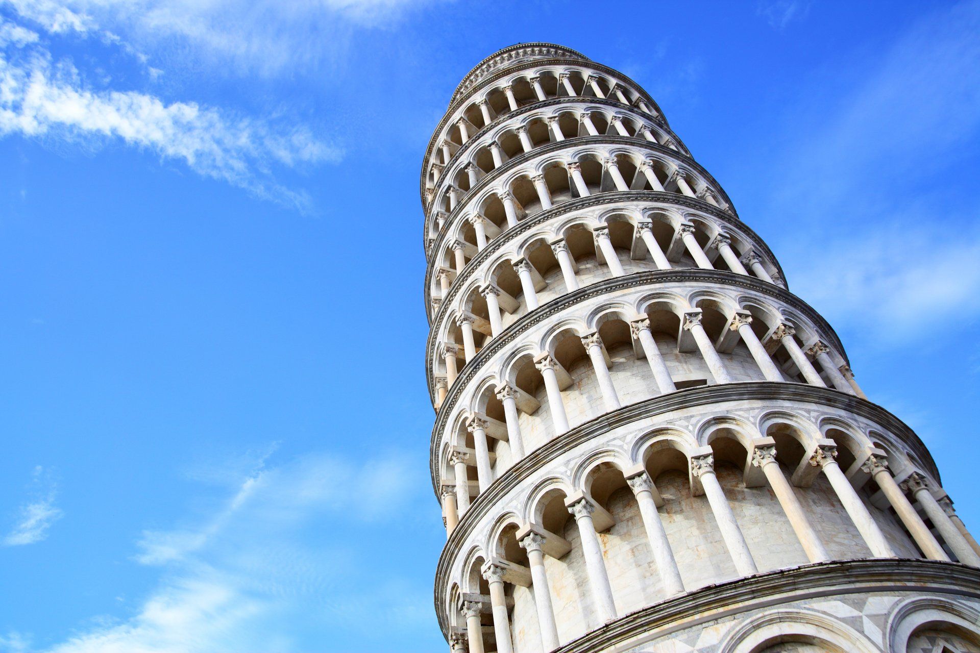 Looking up at the leaning tower of pisa against a blue sky