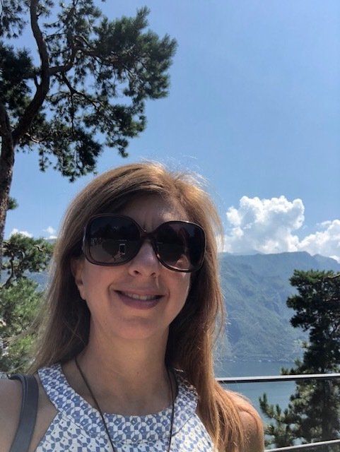 A woman wearing sunglasses is smiling in front of mountains