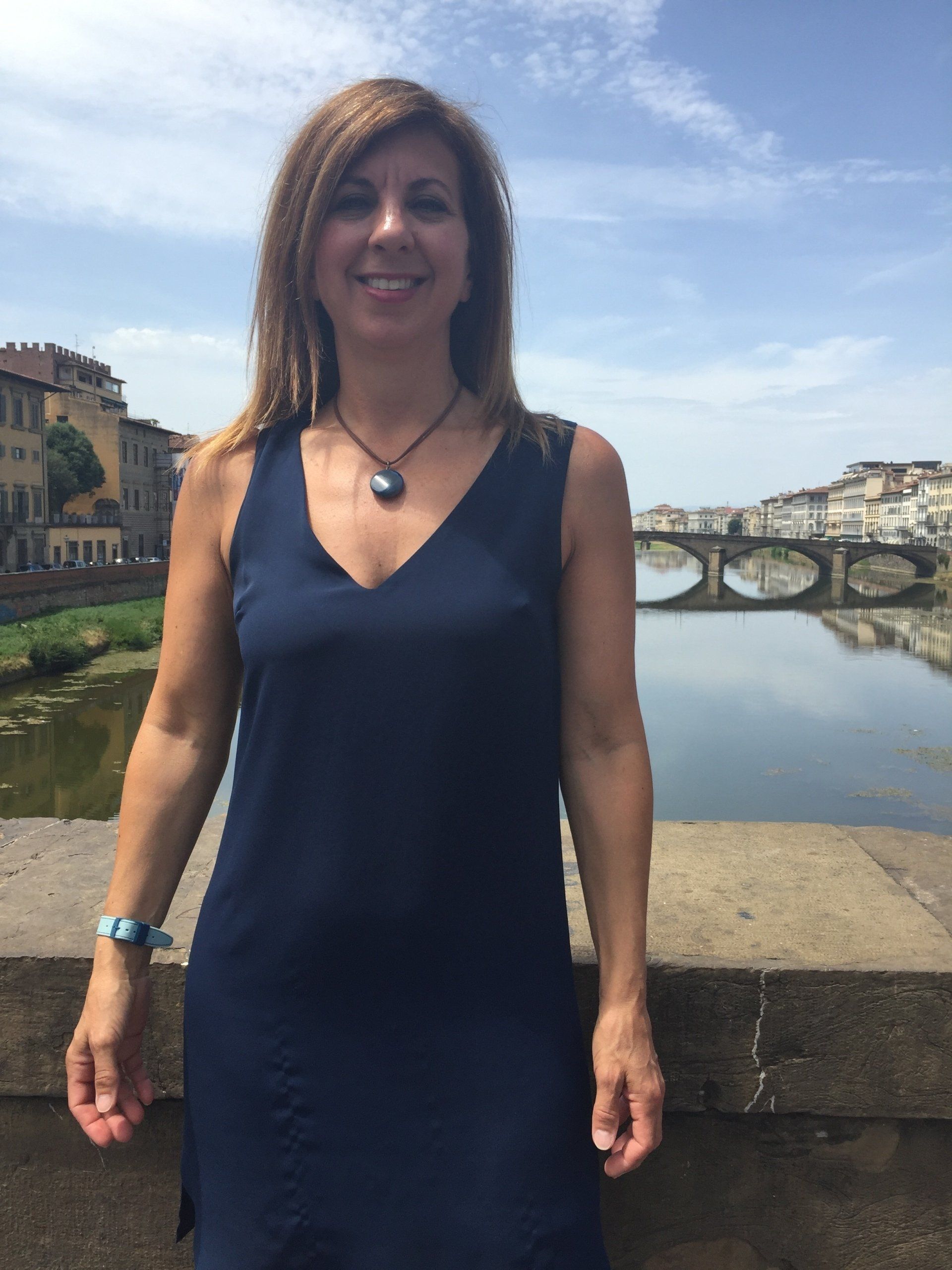A woman in a blue dress is standing in front of a river
