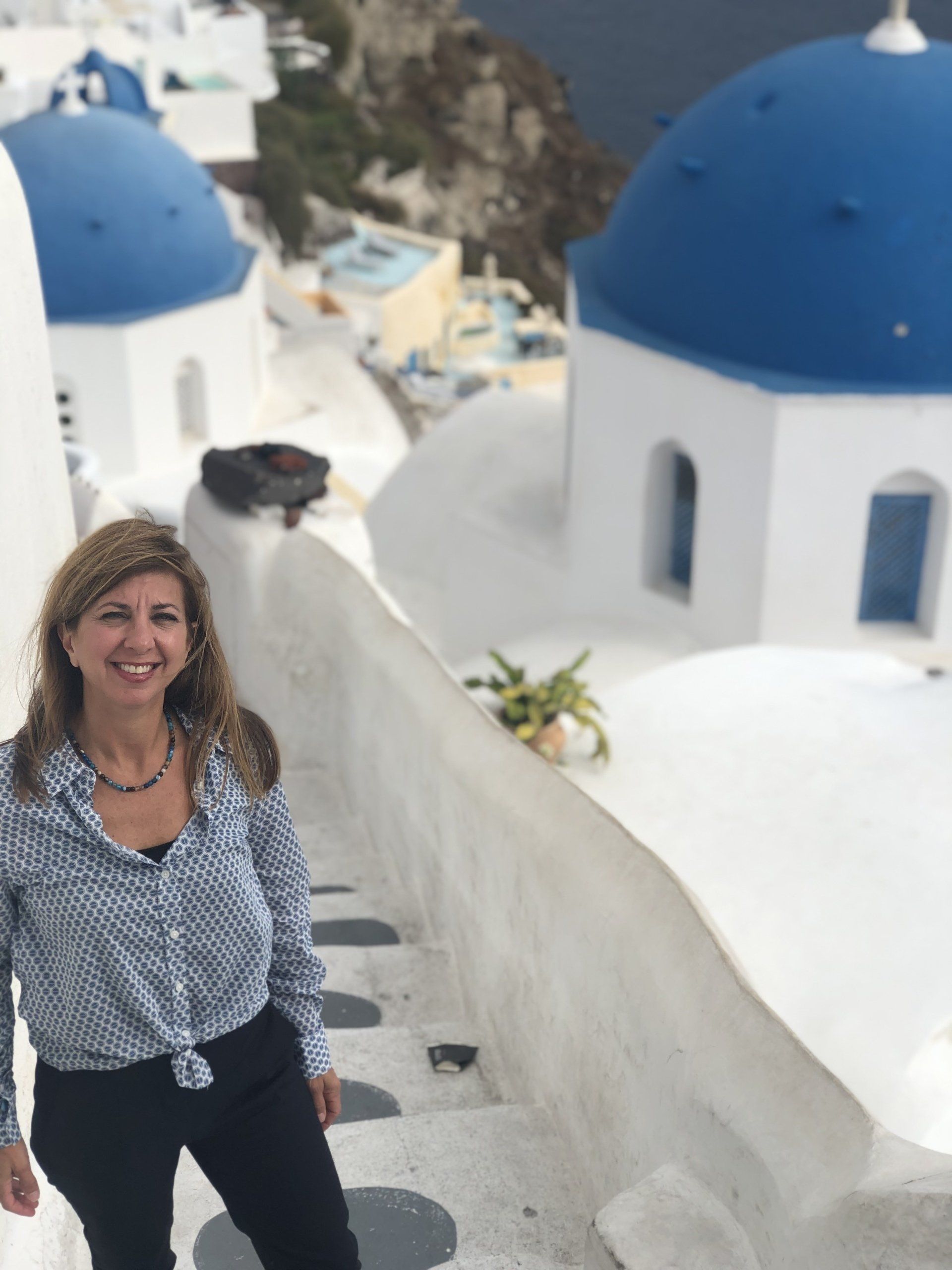 A woman is standing on a set of stairs with blue and white domes in the background