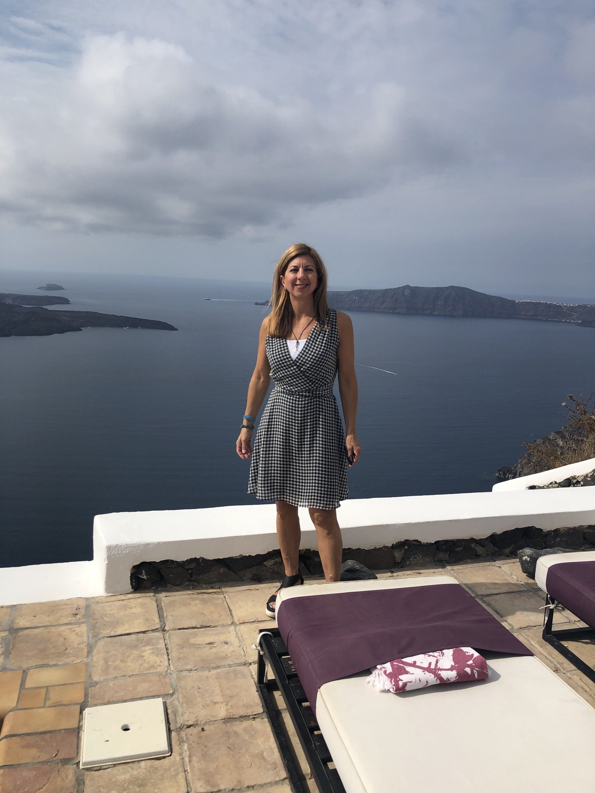 A woman in a dress is standing on a balcony overlooking the ocean.