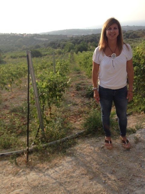 A woman in a white shirt and jeans is standing in a field.
