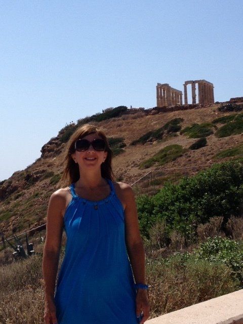 A woman in a blue dress is standing in front of a hill