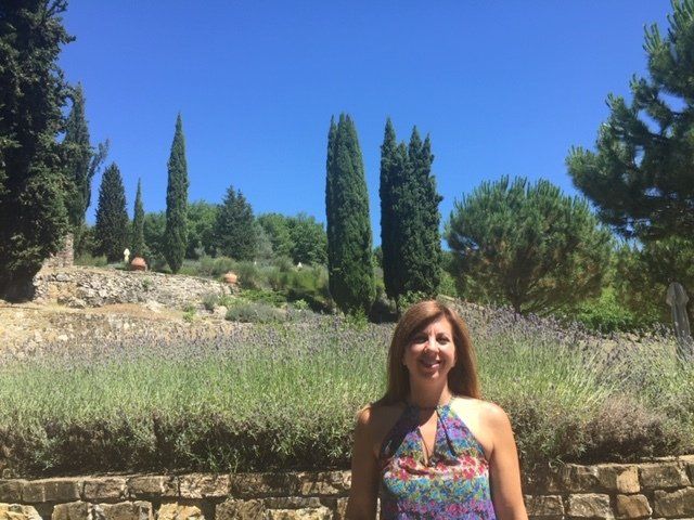 A woman in a purple dress is standing in a field of lavender.