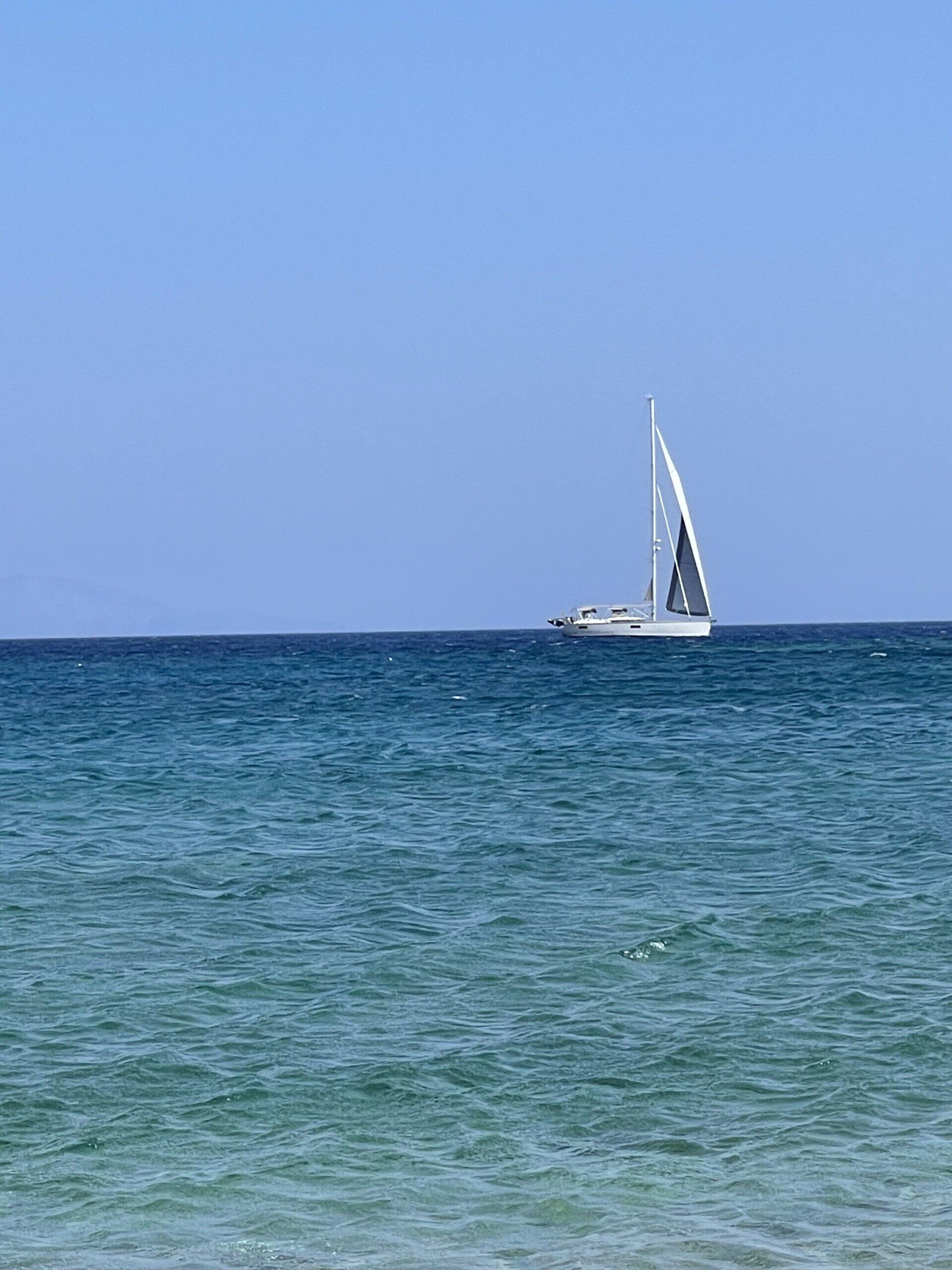 A sailboat is floating on top of a large body of water.