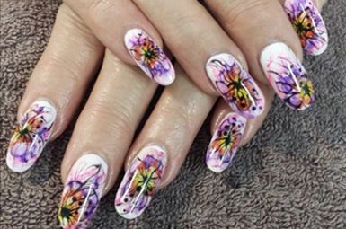 A close up of a woman 's nails with flowers painted on them