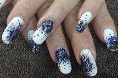 A close up of a woman 's nails with a feather design