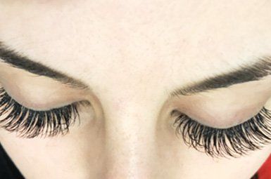 A close up of a woman 's eyelash extensions and eyebrows.