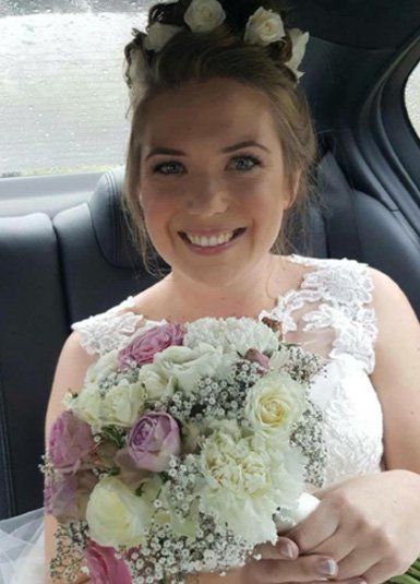 A woman in a wedding dress is holding a bouquet of flowers.
