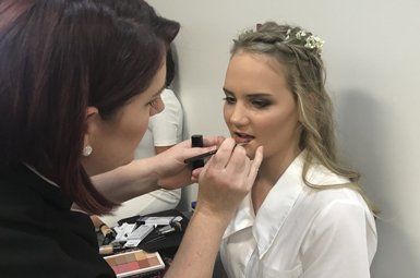 A woman is applying makeup to another woman 's face.