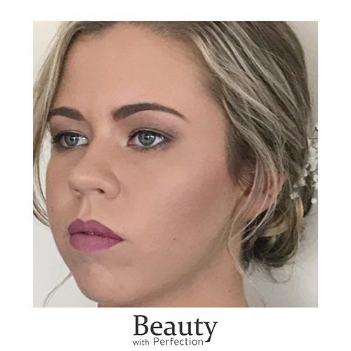 A close up of a woman 's face with makeup and a bun.