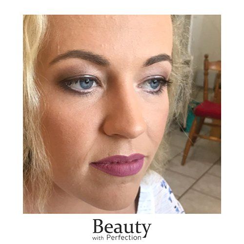 A close up of a woman 's face with purple lipstick and professional makeup.