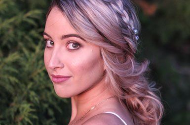 A close up of a woman 's face with a braid in her hair.