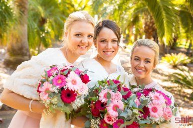 A bride and her bridesmaids are posing for a picture while holding bouquets of flowers.