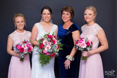 A bride and her bridesmaids are posing for a picture while holding bouquets of flowers.