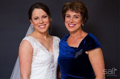 A bride and her mother are posing for a picture together
