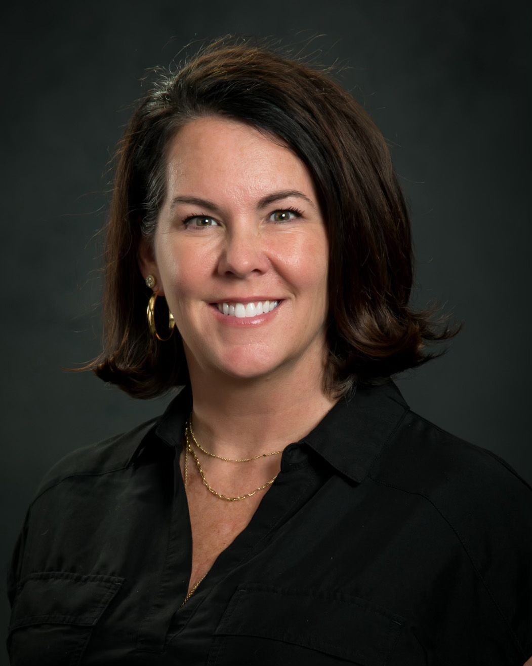 A woman in a black shirt is smiling for the camera.