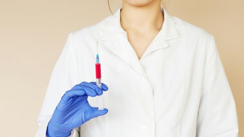 A female doctor is holding a syringe in her hand.